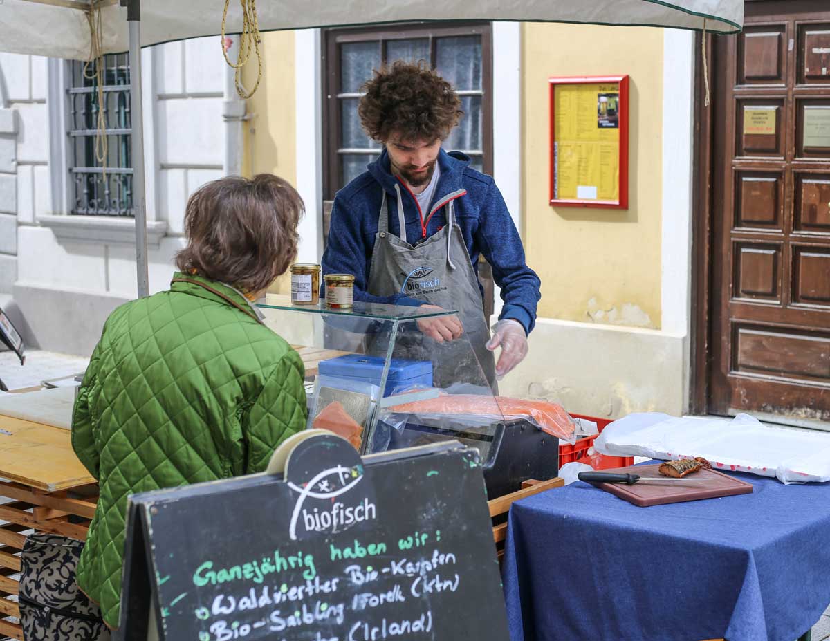 Biofisch Mitarbeiter bereitet Lachs für Kundin am Langegasse Markt vor